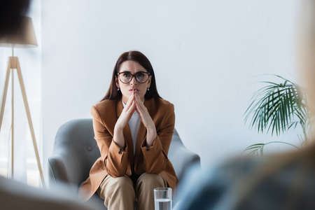 psychologist in armchair listening to blurred patients during consultation