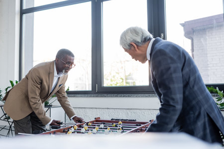 senior interracial businessmen playing table football in officeの写真素材