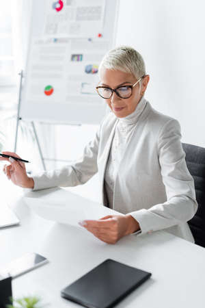 senior businesswoman in glasses looking at document in officeの写真素材