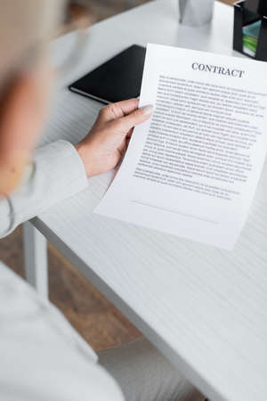 blurred senior businesswoman holding contract in office
