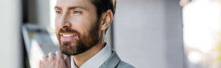 Positive businessman in formal wear looking away in office, bannerの写真素材