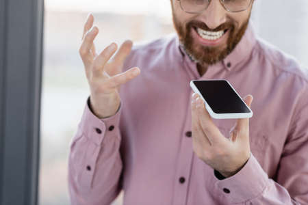 Cropped view of angry businessman recording voice message on smartphone in officeの写真素材