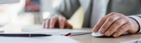 Cropped view of businessman using computer mouse in office, bannerの写真素材