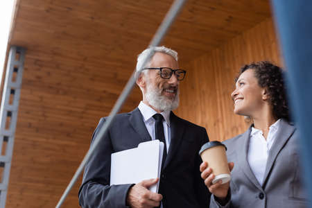 smiling middle aged businessman talking to african american colleague outdoorsの写真素材