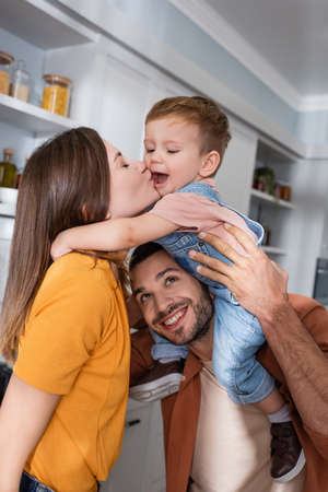 Woman kissing child near husband at homeの写真素材