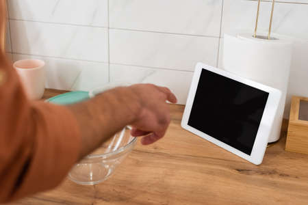 Cropped view of man pointing at digital tablet with blank screen near bowl in kitchen