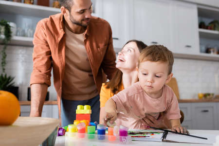 Toddler kid holding paint near building blocks and parents at homeの写真素材