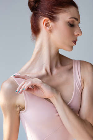 sensual young ballerina in bodysuit dancing isolated on grayの写真素材