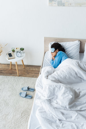 high angle view of african american woman in eye mask sleeping in bedの写真素材