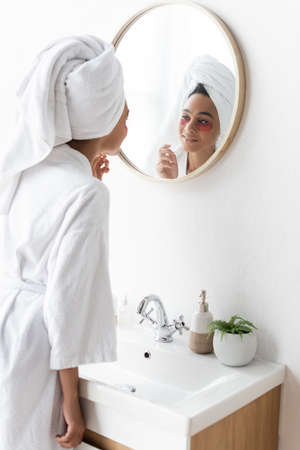 cheerful african american woman in eye patches looking at mirrorの写真素材