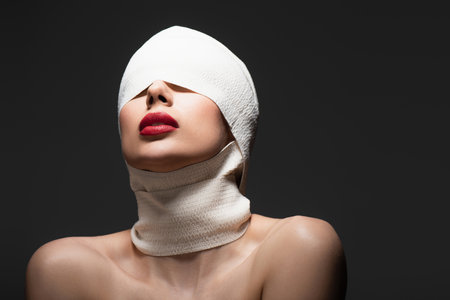 woman in elastic bandage with bare shoulders posing isolated on blackの写真素材