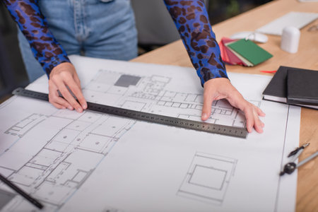 cropped view of interior designer holding ruler while working with blueprintの写真素材