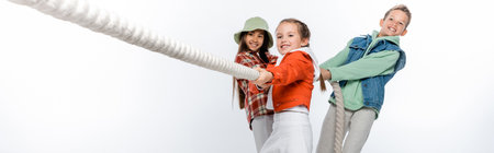 preteen children pulling rope while playing tug of war game on white, banner