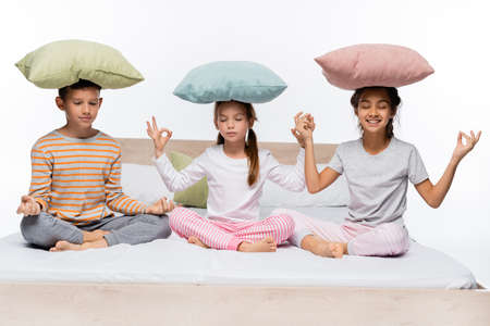happy kids with pillows on heads meditating isolated on whiteの写真素材