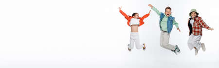 full length of stylish kids smiling while levitating on white, bannerの写真素材