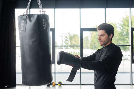 Brunette boxer wearing glove near punching bag in sports centerの写真素材
