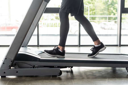 Cropped view of sportsman training on treadmill in sports center