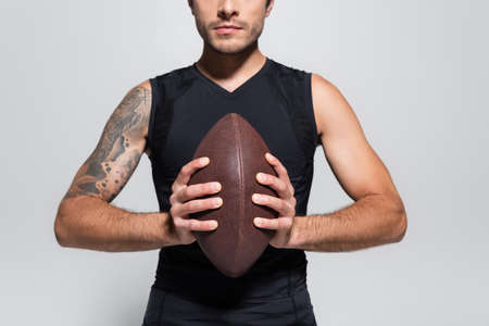 Cropped view of sportsman holding rugby ball isolated on greyの写真素材