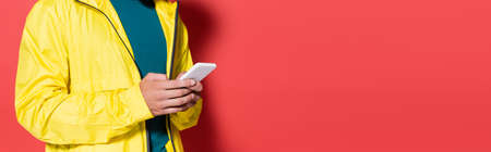 Cropped view of sportsman using mobile phone on red background, bannerの写真素材