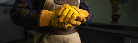 Cropped view of welder in gloves standing in factory, bannerの写真素材