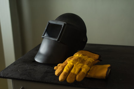 Welding mask with visor and gloves on table in factoryの写真素材
