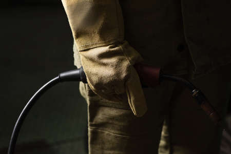 Cropped view of welder in glove holding welding torch in factoryの写真素材