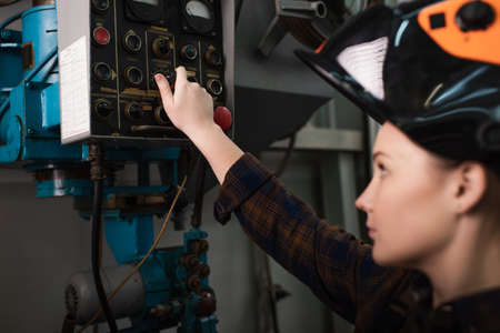 Side view of blurred welder in helmet switching welding machine in factoryの写真素材