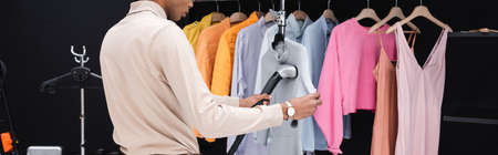 cropped view of african american stylist using steamer while cleaning clothes in dressing room, bannerの写真素材