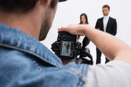 photographer with digital camera taking photo of blurred models isolated on whiteの写真素材