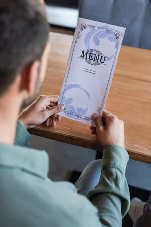 cropped view of blurred man holding menu in restaurantの写真素材