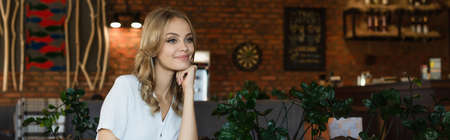 young blonde woman looking away and smiling in cafe, bannerの写真素材