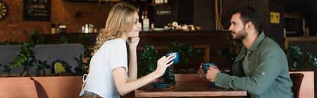 side view of happy couple looking at each other while holding coffee cups, bannerの写真素材