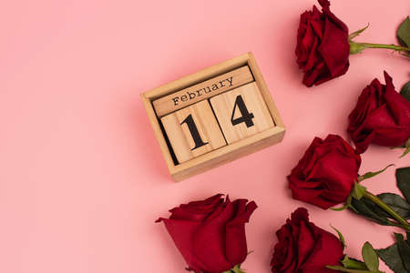 top view of red roses near calendar with 14 february lettering on pinkの写真素材