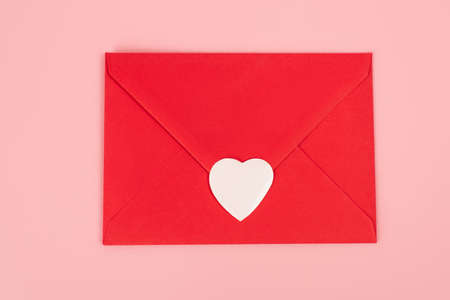 top view of paper heart sticker on red envelope isolated on pinkの写真素材