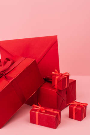 red wrapped gift boxes and envelope on pinkの写真素材