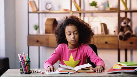 curly african american child reading book at homeの写真素材