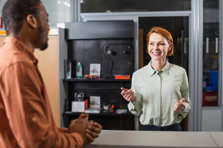 positive car dealer gesturing while talking to blurred african american manの写真素材