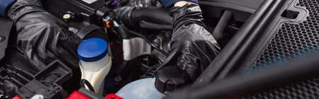 partial view of mechanic in work gloves checking engine compartment of vehicle in car service, bannerの写真素材