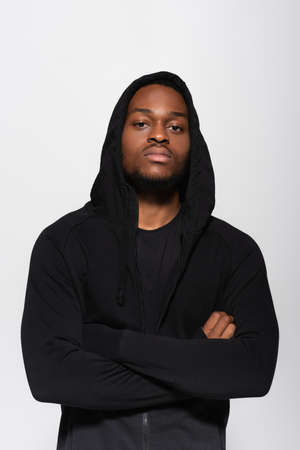 young african american man in hoodie standing with crossed arms isolated on grey