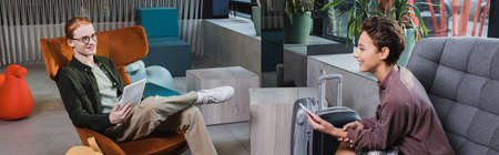 Positive young couple using devices near suitcases in hotel lobby, banner