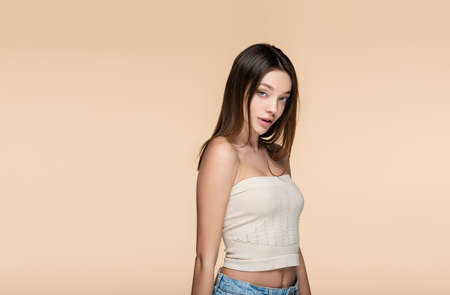 brunette and pretty woman in crop top with bare shoulders isolated on beige