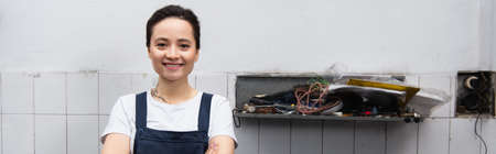 Cheerful mechanic looking at camera in car service, banner