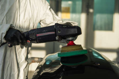 Cropped view of workman polishing car part while working in garage