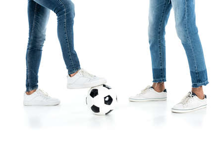 cropped view of interracial men in jeans and sneakers playing football on whiteの写真素材