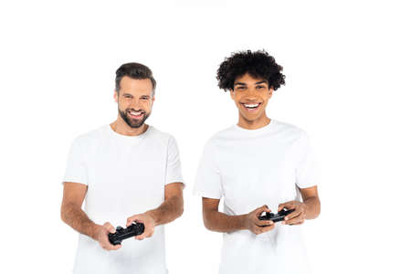 KYIV, UKRAINE - DECEMBER 5, 2021: happy interracial men in t-shirts gaming with joysticks isolated...