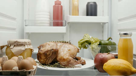 roasted turkey prepared for thanksgiving dinner near fresh vegetables, fruits and containers with food in fridgeの写真素材