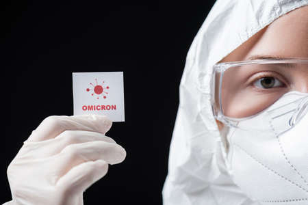 cropped view of doctor in hazmat suit holding card with lettering and bacteria icon isolated on blackの写真素材