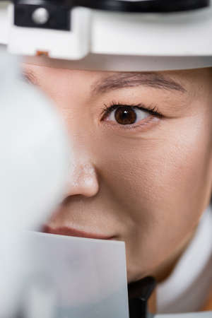 close up view of asian optometrist working with vision screener on blurred foreground