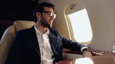 Smiling businessman in eyeglasses sitting in private plane