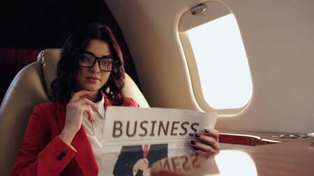 Young businesswoman reading blurred newspaper in private planeの写真素材